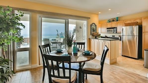 A modern kitchen with a dining area, large windows, and a view of the ocean.