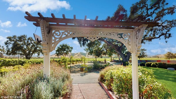 Una estructura de pérgola con un sendero que atraviesa un jardín.