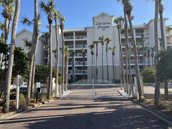 Welcome to Crystal Dunes, a tropical getaway with a grand entrance and beautiful palm trees surrounding the building.