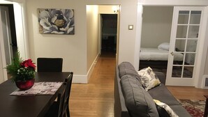 A modern living room with a dining table, gray sofa, and a large floral painting on the wall. - Sunny Family Friendly 2 Bd1 Ba Sleeps 6, Safe, Fun & Walkable Grand Lake Oakland (Oakland)