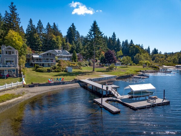 A waterfront property with a dock, a grassy area, and several houses. - Lakefront Paradise: Private Beach, Water Sports, Stunning Sunsets, Sleeps 8 (Bellingham)