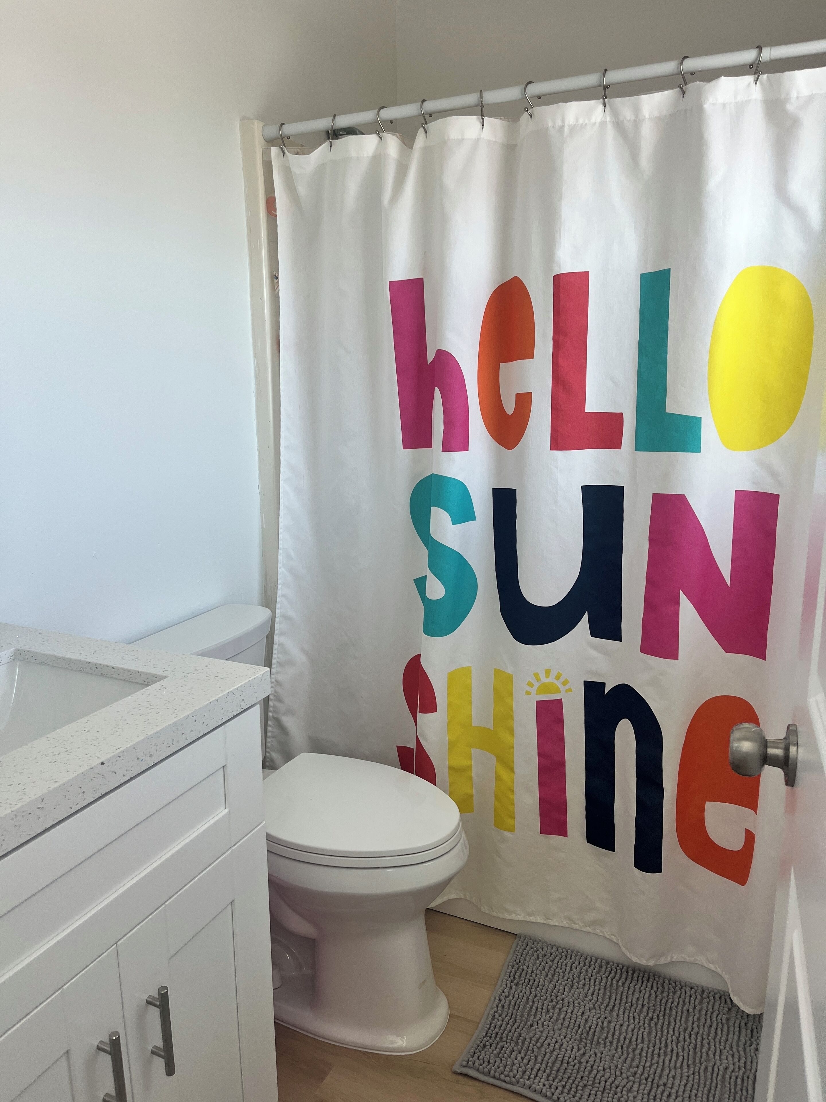 Ein Badezimmer mit Toilette, Waschbecken und einer Duschtrenne mit farbigem Text.