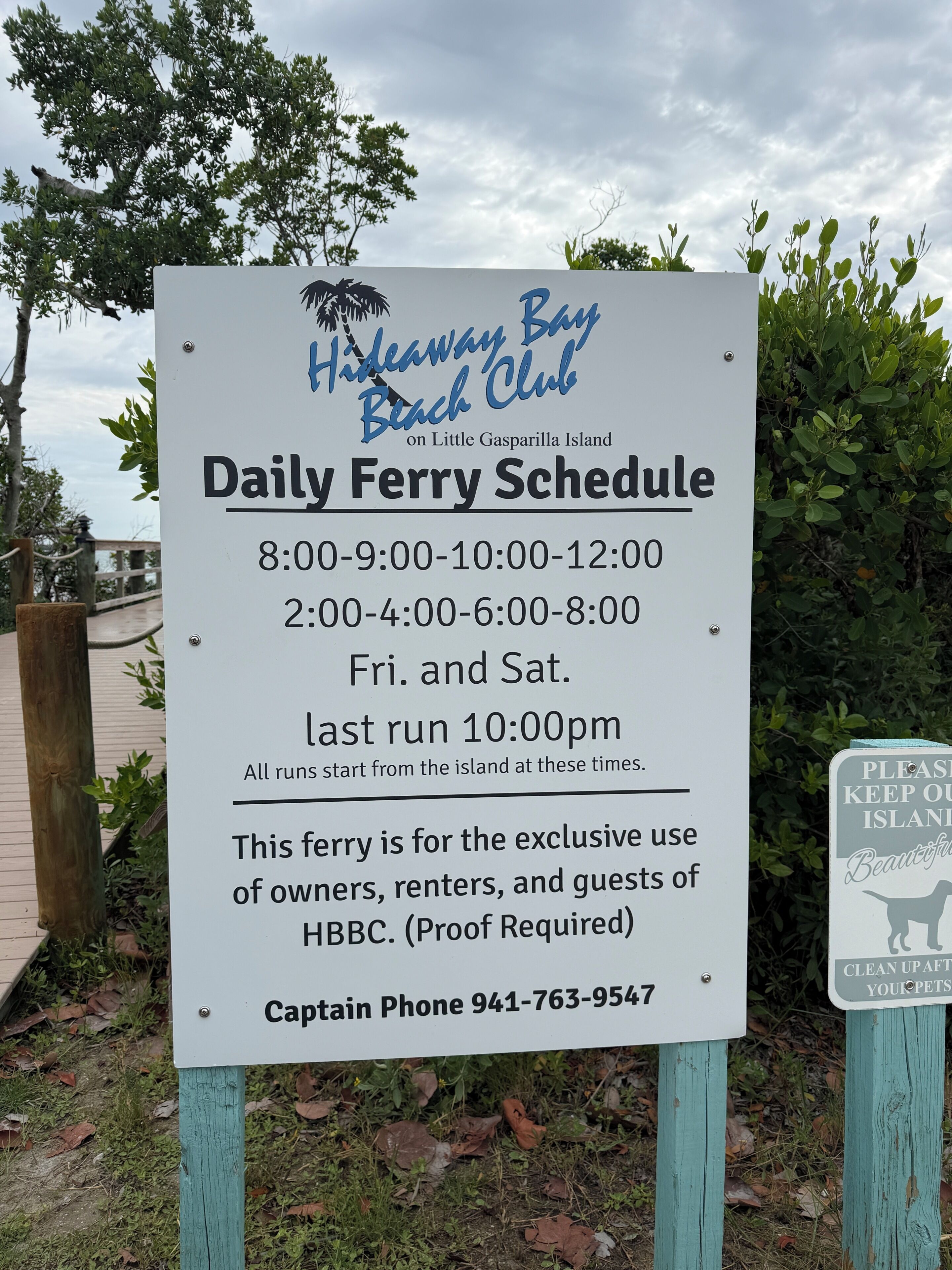 Een bord met een veerbootdienstregeling voor de Hideaway Bay Beach Club op Little Gasparilla Island.