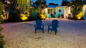 Two blue chairs facing a house with a porch, surrounded by palm trees and a gravel driveway. - Star Fish. 3 Bed 2 Bath. POOL. Daily Rentals (Sarasota)