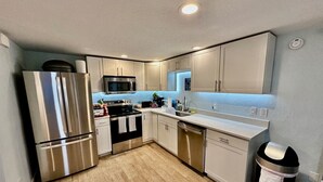 A compact kitchen with stainless steel appliances, white cabinetry, and a wooden floor. - Star Fish. 3 Bed 2 Bath. POOL. Daily Rentals (Sarasota)