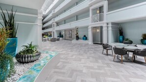 A spacious indoor atrium with a modern design, featuring multiple levels, seating areas, and potted plants. - Stay on the Beach! Guest Favorite | Excellent Reviews | Chairs/Umbrella Included (Santa Rosa Beach)