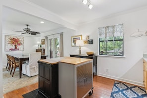 A kitchen with a dining area, a ceiling fan, a window with curtains, and a wall-mounted fish decoration.