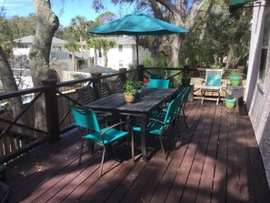 A wooden deck with a table and chairs, surrounded by potted plants and a large umbrella. - Beautiful 4 bed, 5 full bath, East Beach with Pool, 3 houses from East Beach (St Simons Island)