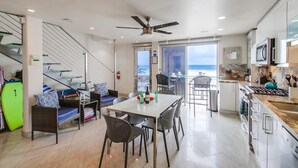 A modern kitchen with a dining area, a staircase, and a view of the ocean. - 2 Levels of Ocean Front + AC + Heart of MB (San Diego)