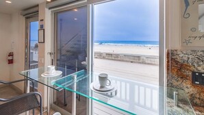 A room with a glass table, two white cups, a fire extinguisher, and a view of the beach. - 2 Levels of Ocean Front + AC + Heart of MB (San Diego)