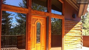 Una cabaña de madera con un amplio ventanal y una terraza.