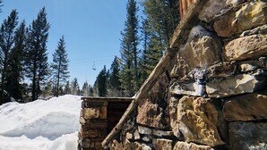 Un edificio de piedra con un nivel superior de madera, rodeado de nieve y árboles.