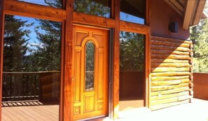 Une cabane en bois dotée d’une grande porte vitrée et d’une terrasse.