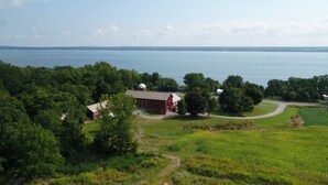 A rural landscape with a red barn, a white silo, and a body of water in the background.