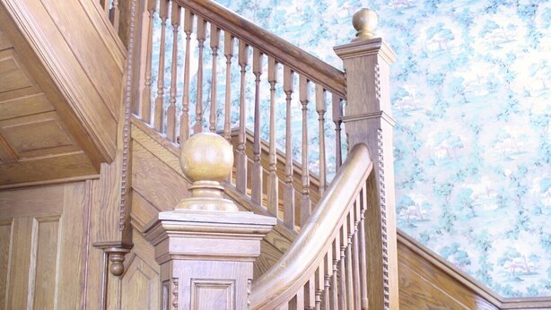 A wooden staircase with a balustrade leading to a landing.