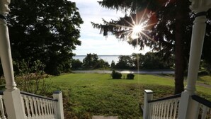 A porch with a view of a grassy area and a body of water.