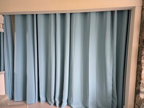Une pièce dotée d’une grande fenêtre recouverte de rideaux bleu clair.