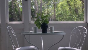 A small table with two chairs, a potted plant, and two white cups. - Cape Cod Pond Cottage (Eastham)