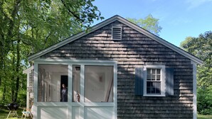 A small, single-story wooden house with a porch and a window. - Cape Cod Pond Cottage (Eastham)