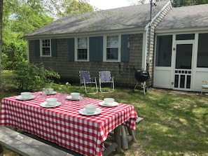 A picnic table set up in a backyard with a house in the background. - Cape Cod Pond Cottage (Eastham)