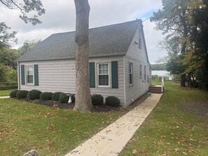 A single-story house with a grey shingled roof, green shutters, and a white door. - Fabulous Waterfront Property in the Heart of Wine Country (Peconic)