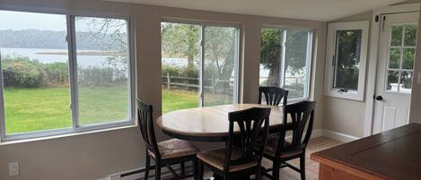 A kitchen with a dining table and chairs, large windows, and a view of a lake.