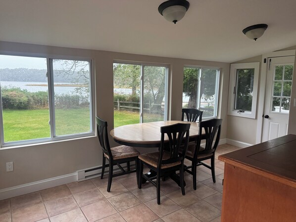 A kitchen with a dining table and chairs, large windows, and a view of a lake. - Fabulous Waterfront Property in the Heart of Wine Country (Peconic)