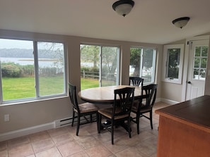 Una cocina con mesa y sillas, ventanas amplias y vista a un lago.