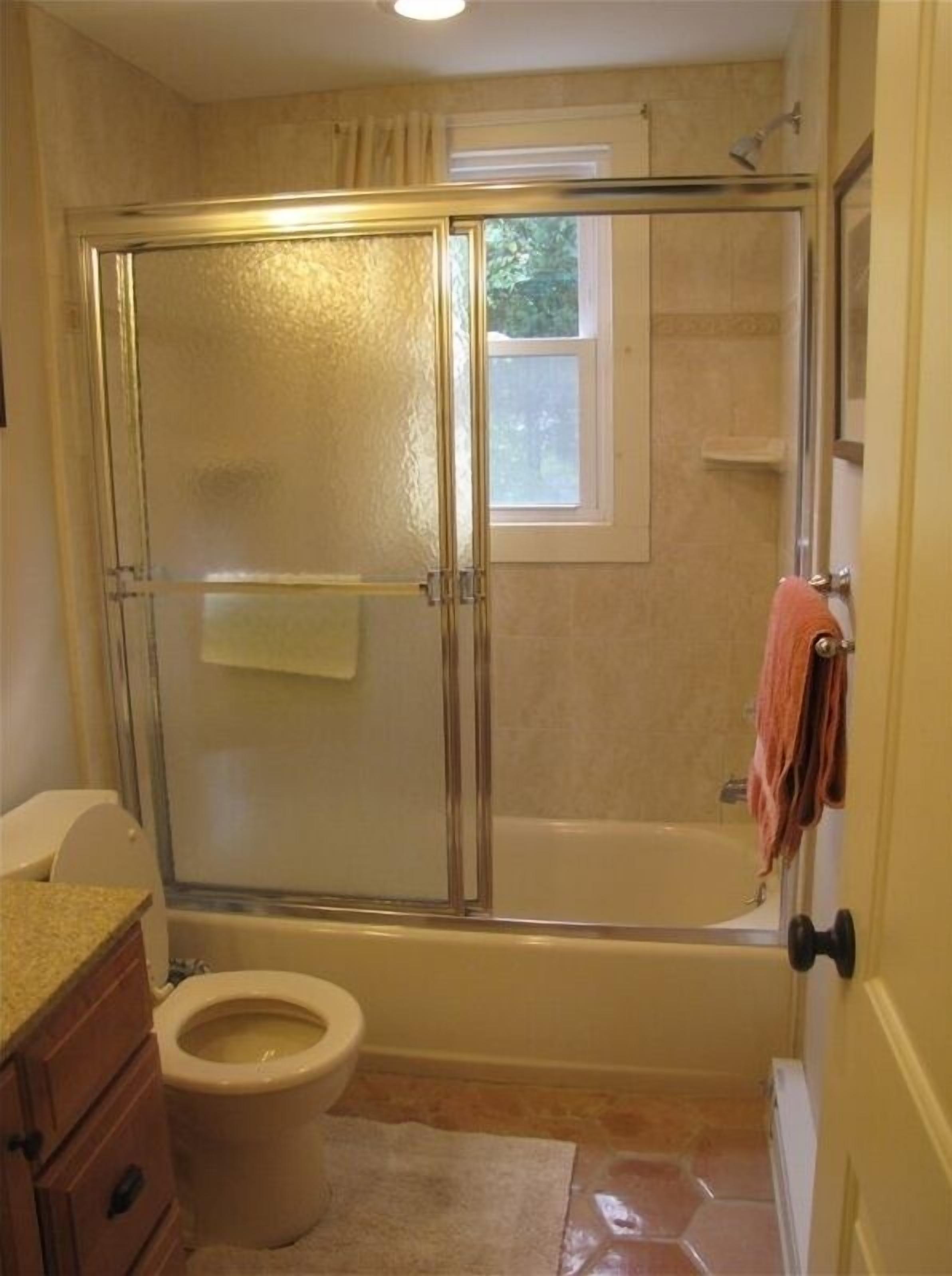 Une salle de bain avec une douche à parois de verre, une baignoire, des toilettes et une fenêtre.