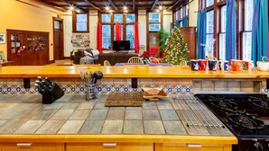 A spacious kitchen with a long counter, a gas stove, and a dining area with a Christmas tree.
