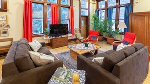 A cozy living room with a large TV, two sofas, a coffee table with a decorative centerpiece, and a bookshelf.