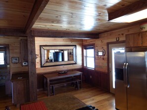 L’intérieur d’une cabane en bois comprend un coin cuisine équipé d’un réfrigérateur, d’un banc en bois et d’un grand miroir.