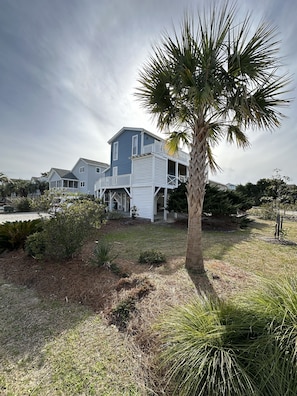 A two-story house with a porch and a palm tree in the yard.