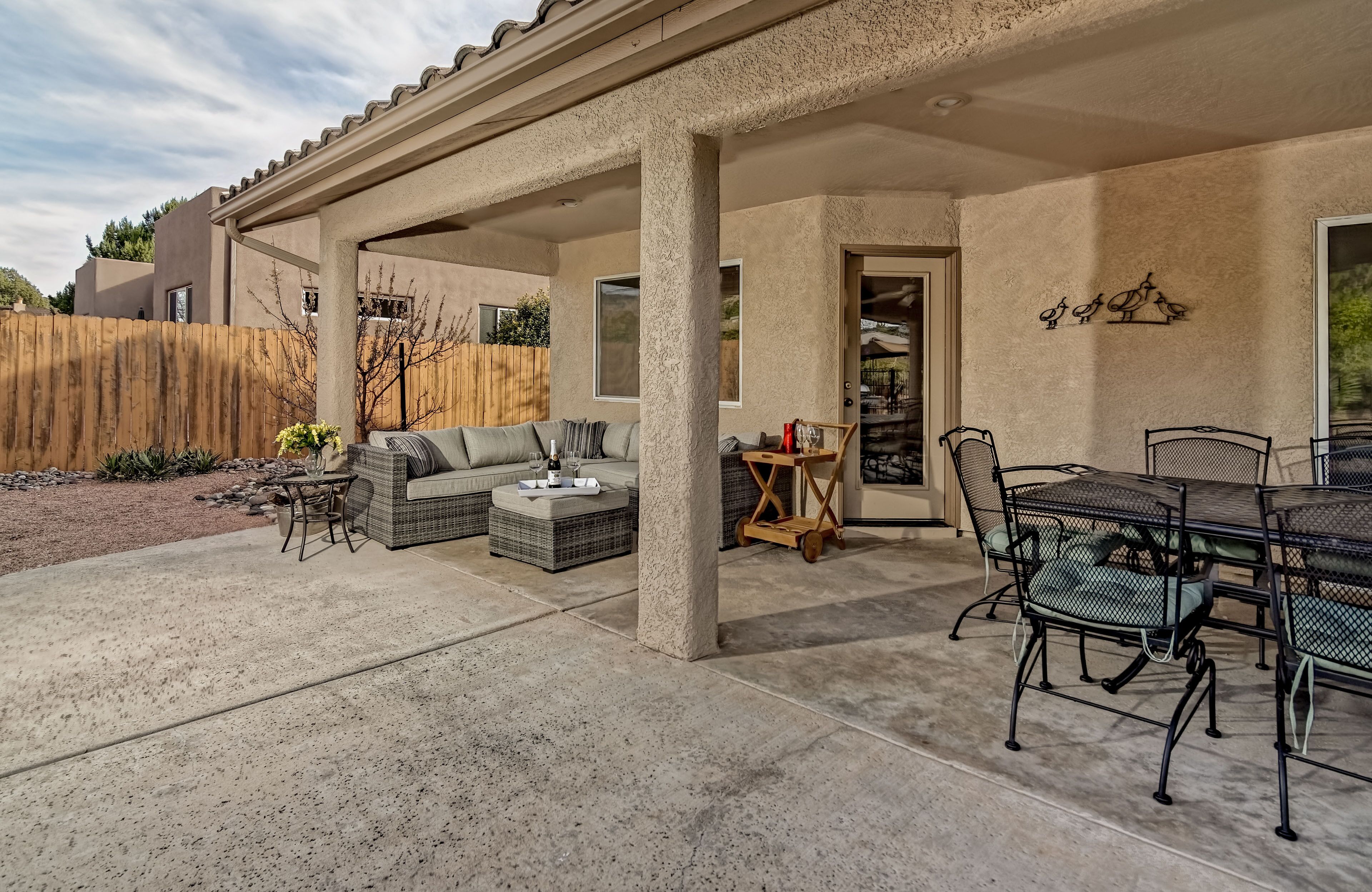 A covered patio area with outdoor furniture, including a sofa, chairs, and a dining table.