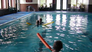 Una piscina interior con agua cristalina, una silla de salvavidas y un cartel en la pared.