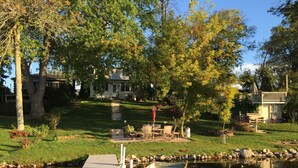 A dock with boats, a grassy area, and a house in the background. - Family And Pet-Friendly On Waubeesee Lake ~ Includes Kayaks! (Wind Lake)