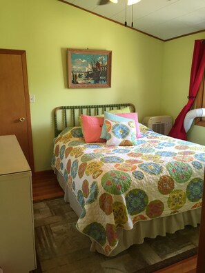 Un dormitorio con cama, un cuadro, aire acondicionado y una puerta.