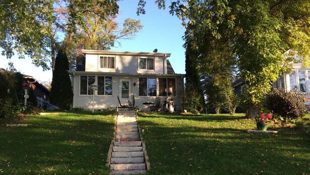 A two-story house with a front porch, a stone pathway leading to the entrance, and a well-maintained lawn. - Family And Pet-Friendly On Waubeesee Lake ~ Includes Kayaks! (Wind Lake)