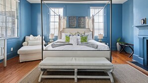 A bedroom with a four-poster bed, a bench, and a fireplace. - Southern Ease Contemporary Flair | The Charleston (Charleston)