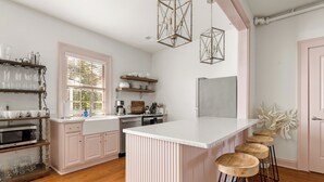 A modern kitchen with a central island, bar stools, and pendant lighting. - Southern Ease Contemporary Flair | The Charleston (Charleston)