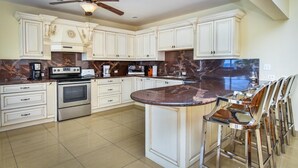 Une cuisine moderne avec des meubles blancs, un îlot central et un ventilateur de plafond.