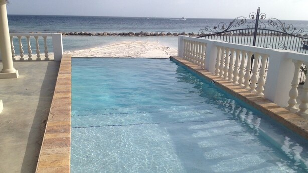 Une piscine aux eaux cristallines, avec vue sur la mer et un rivage rocheux.