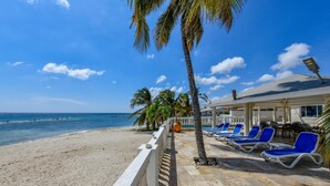 Un hôtel situé en bord de mer, doté d’une piscine, de chaises longues et offrant une vue sur l’océan.