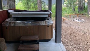 Puukuvioitu poreallas, jossa on puinen reunus ja penkki, ja josta avautuu näkymä metsäiselle alueelle.