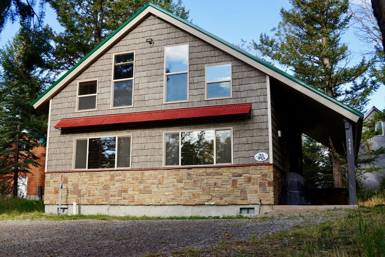 Une maison à deux étages, avec des fondations en pierre et un toit rouge.
