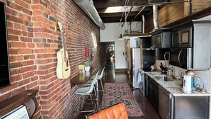 Una cucina con parete in mattoni, una chitarra e un'area pranzo con sedie e tappeto.