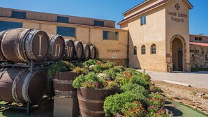 Een wijnmakerij met grote houten vaten en een gebouw met de tekst 'Inwood Estates Vineyards'.