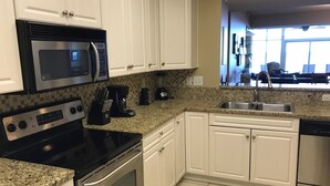 A modern kitchen with white cabinets, a granite countertop, stainless steel appliances including a stove, oven, microwave, and dishwasher. - Luxurious and Elegant, 4BR Ocean Front, Get away! Ocean Blue - Myrtle Beach, SC! (Myrtle Beach)
