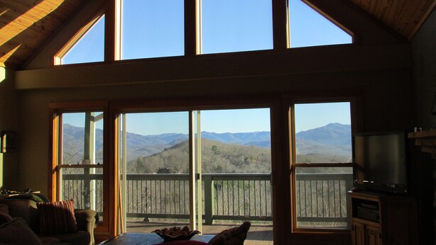 A spacious room with large windows offering a view of mountains.