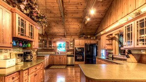 Une cuisine spacieuse, dotée de meubles en bois, d’un îlot central et d’appareils électroménagers modernes.